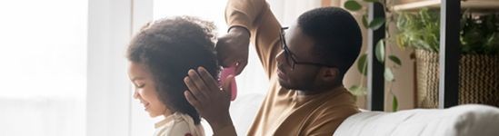 Father brushing his daughters hair.