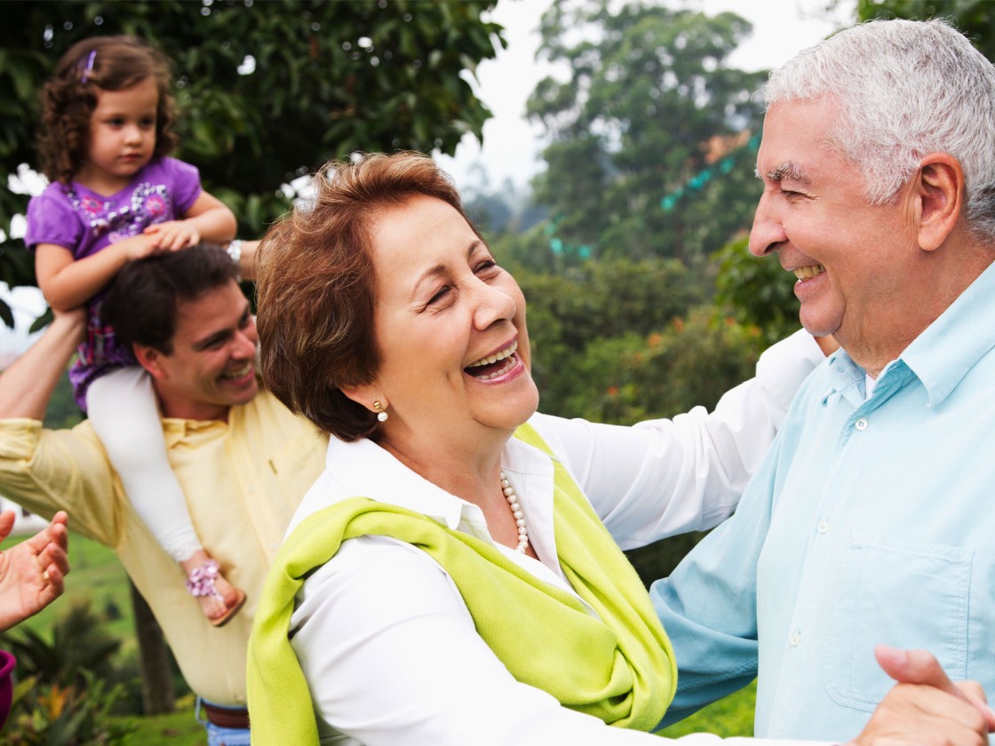 Senior couple dancing with family in the background