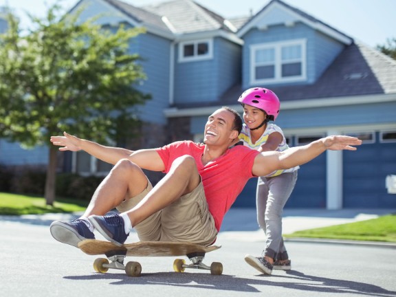 Dad on skateboard with arms out laughing